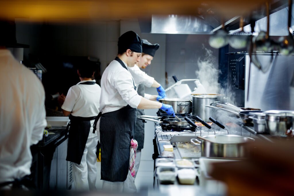 Chefs preparing food at cooking stations in a commercial test kitchen
