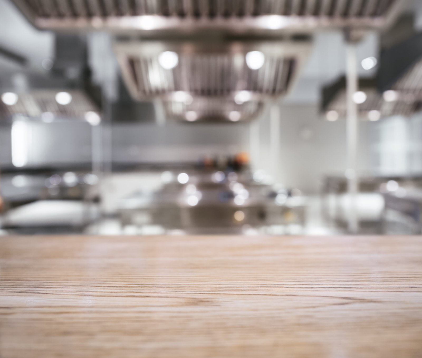Commercial test kitchen with stainless-steel cooking equipment and a wooden work surface