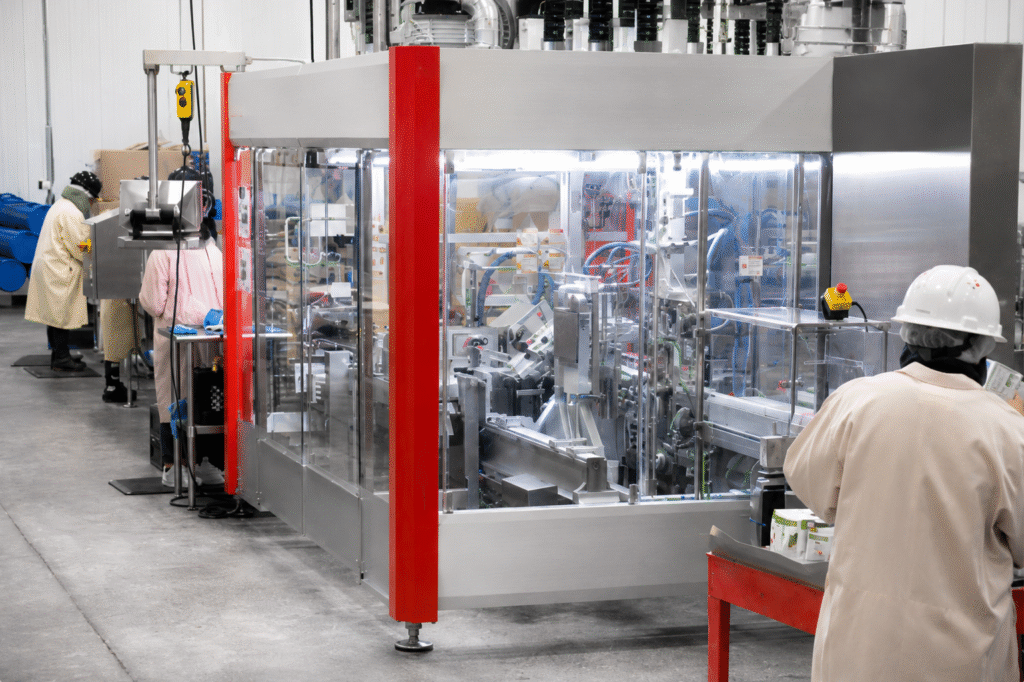 Workers operating automated packaging equipment inside an APC food production facility