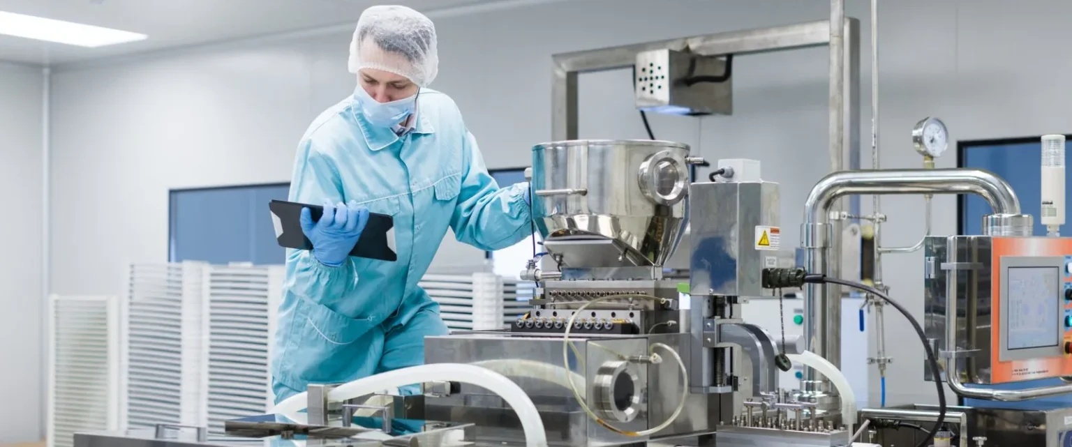 Food production technician reviewing process equipment in a clean manufacturing facility