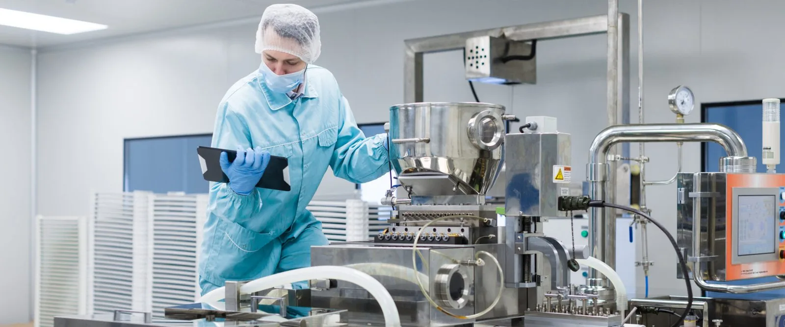 Food production technician reviewing process equipment in a clean manufacturing facility